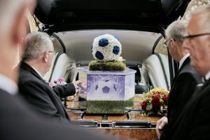 Football themed coffin with football-shaped floral arrangement