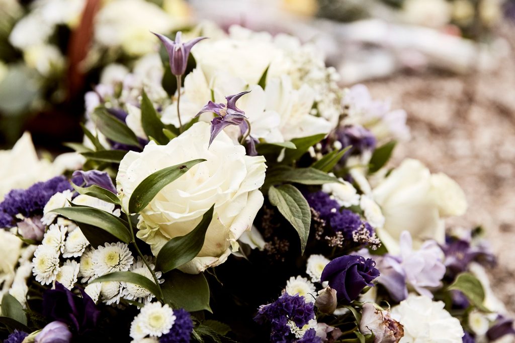 Funeral flower arrangement with white and purple roses