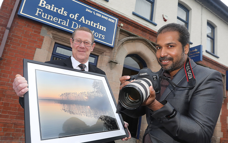 A man with a large camera and a framed photograph